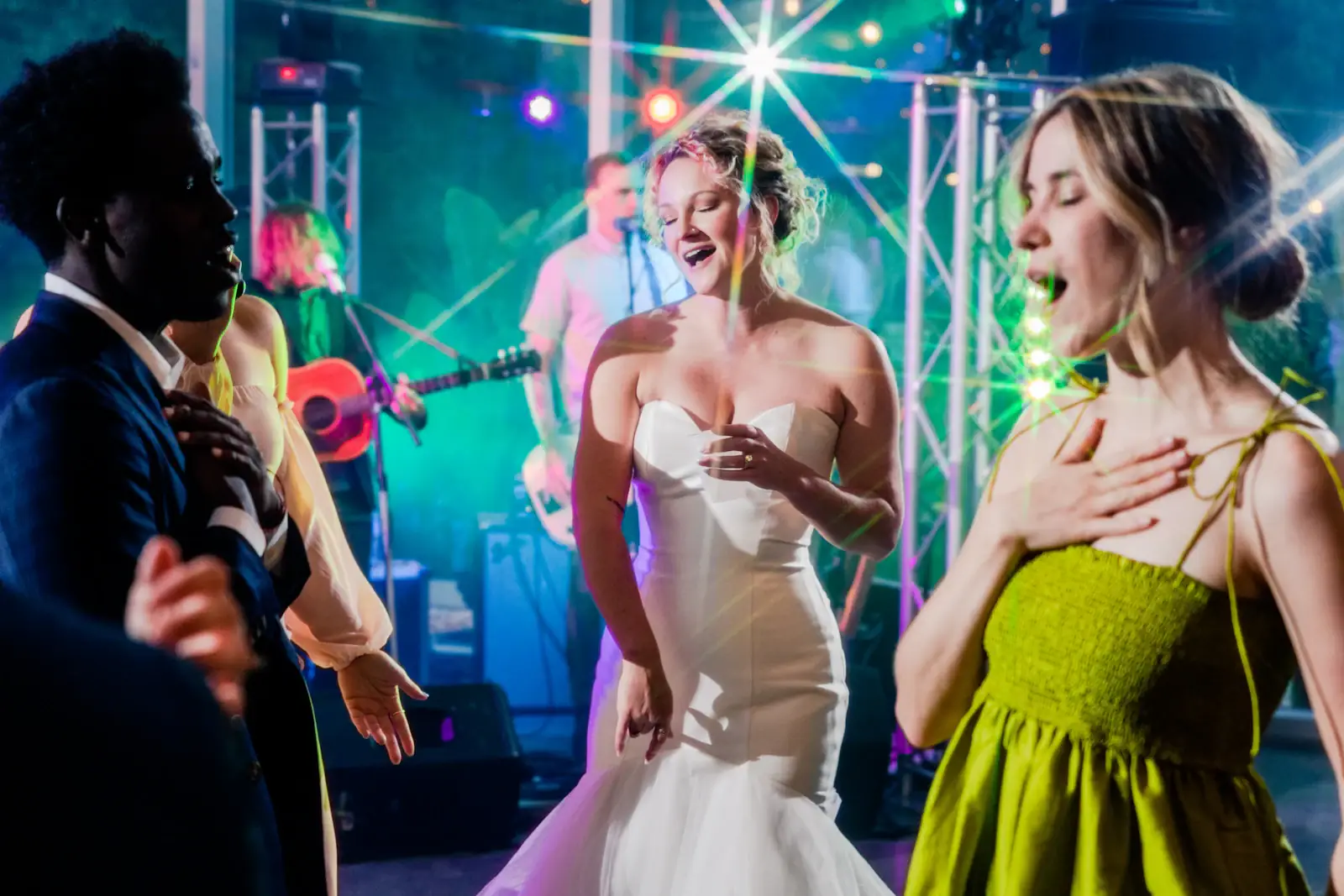 Bride dancing with friends under coloured lights